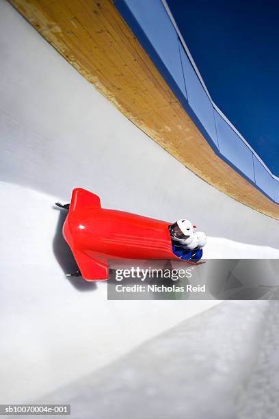 four men bobsled racing down track, high angle view - bobsleigh team stock pictures, royalty-free photos & images
