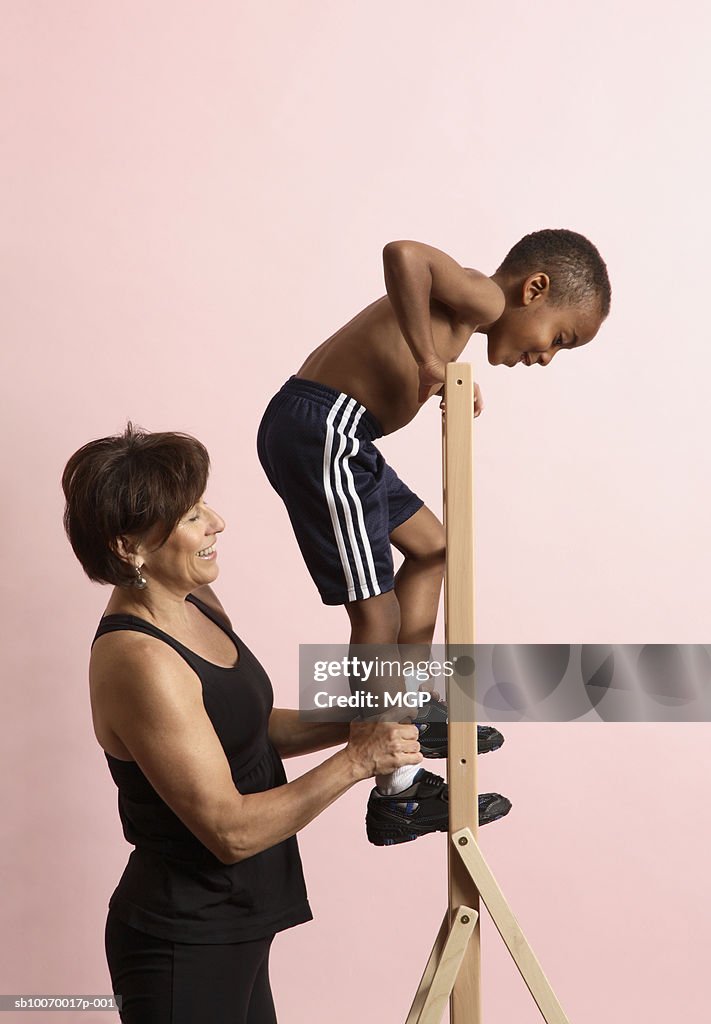 Physical therapist doing exercises with boy (4-5), studio shot, side view