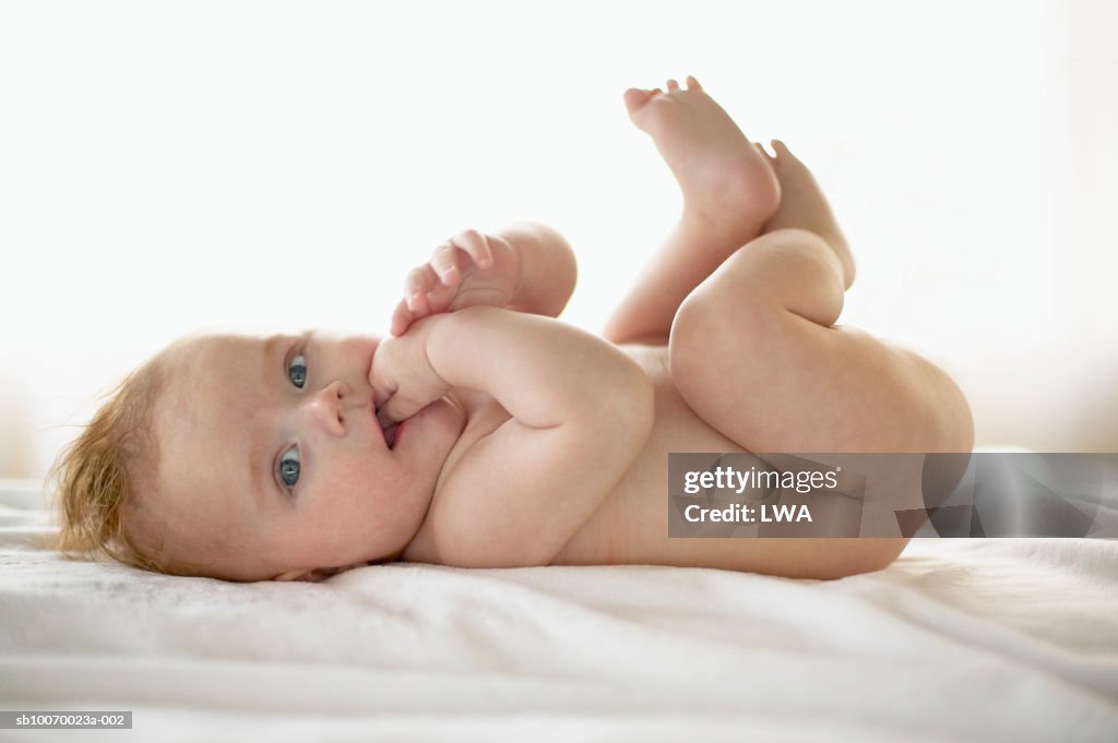 Baby boy (2-5 months) with finger in mouth, portrait