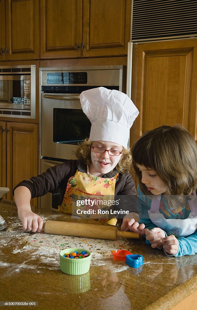 Two girls (4-8) baking in kitchen