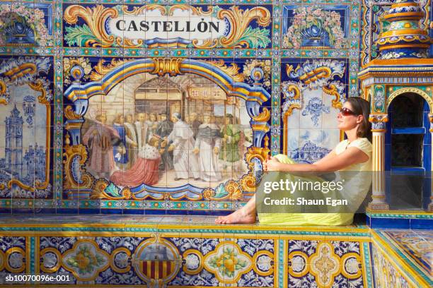 mature woman sitting by tile mosaic saying 'castellon' - castello 個照片及圖片檔