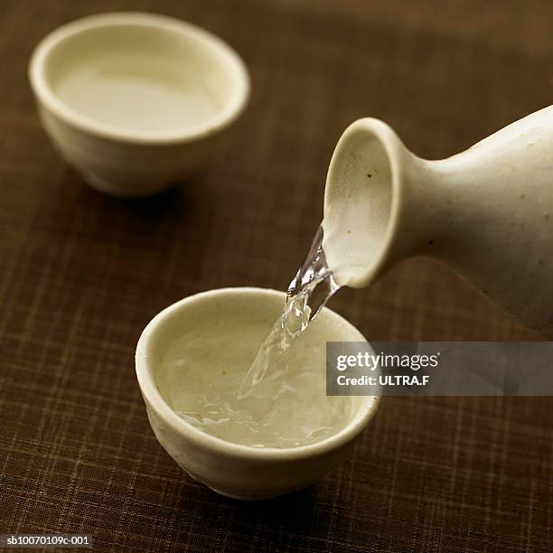 sake is poured into sake cup, studio shot - saquê - fotografias e filmes do acervo