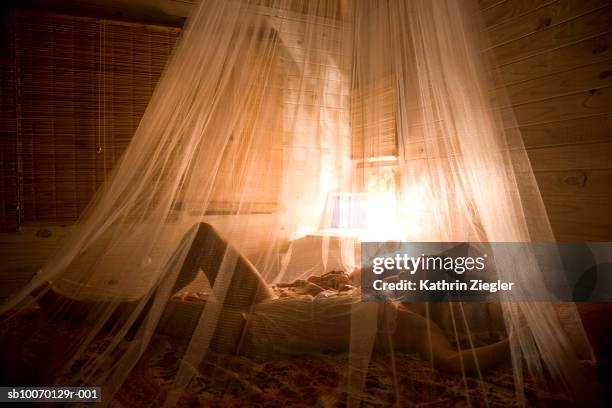 woman sleeping on bed with mosquito net in beach house - mosquito netting stock pictures, royalty-free photos & images