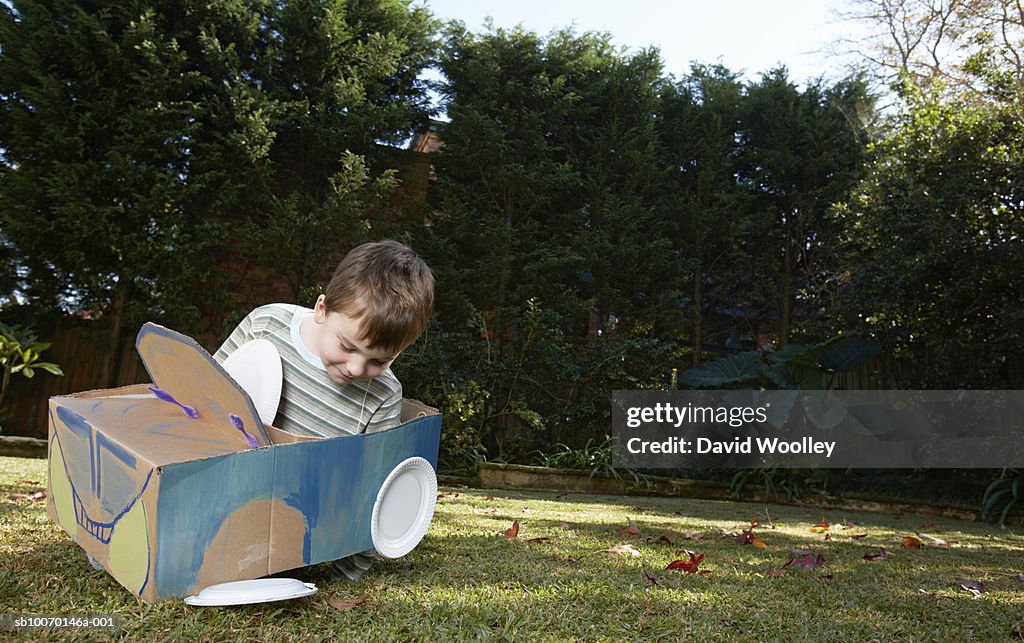 Boy (6-7) playing with car made from cardboard box and plates