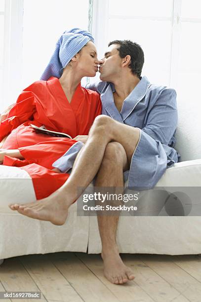 boyfriend and girlfriend wearing dressing gowns kissing on sofa - dressing up ストックフォトと画像