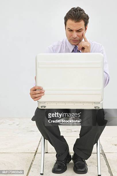 businessman sitting on a chair looking inside a briefcase - inside of ストックフォトと画像