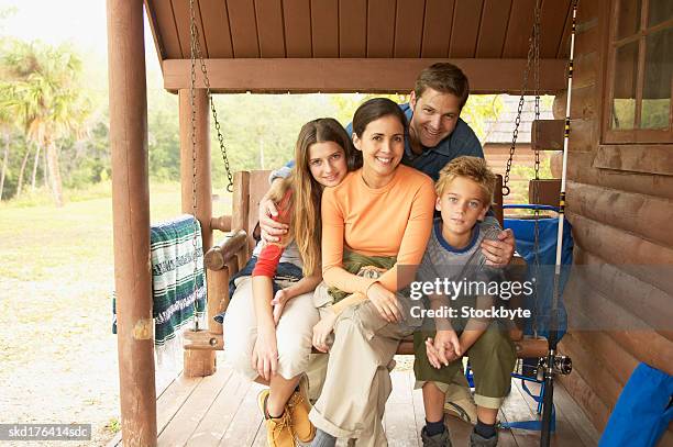 mother father daughter (15-16) and son (10-11) sitting on a garden swing - 1516 stock pictures, royalty-free photos & images