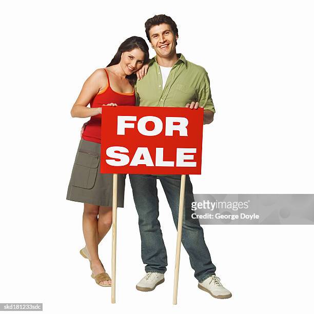 front view portrait of a man and woman holding a for sale sign - for sale korte frase stockfoto's en -beelden