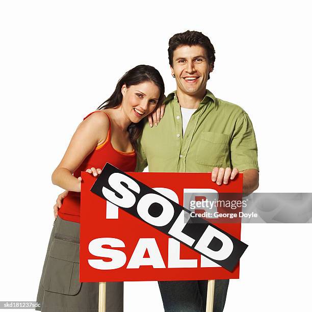 close-up portrait of a man and woman holding a for sale sign - for sale korte frase stockfoto's en -beelden