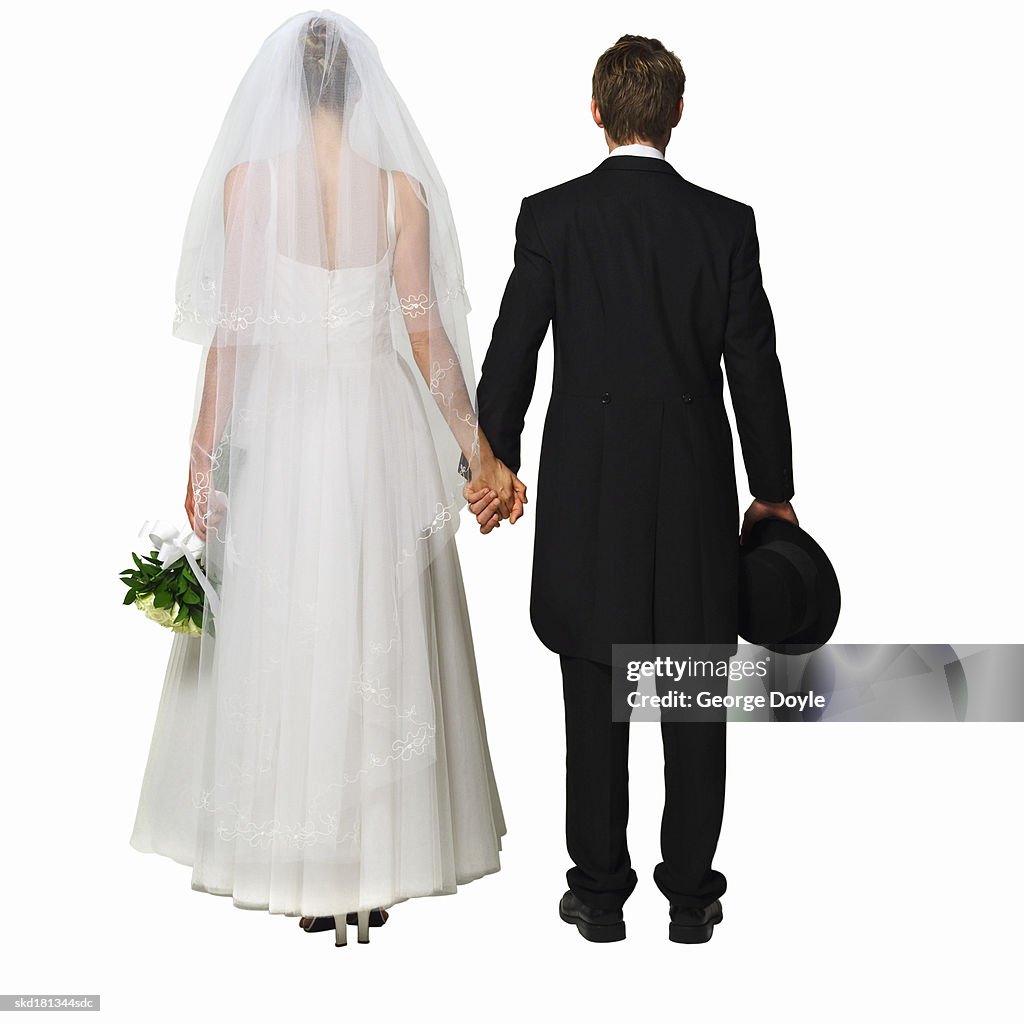 Rear view of a bride holding bouquet and groom holding his hat