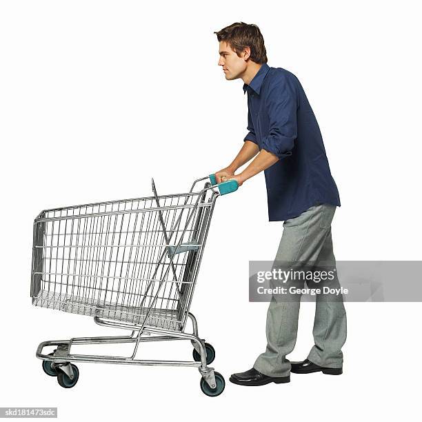 side view of a man pushing a trolley - spingere carrello foto e immagini stock