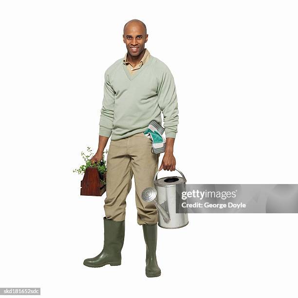 portrait of a man holding a watering can and plant - black boot stock pictures, royalty-free photos & images