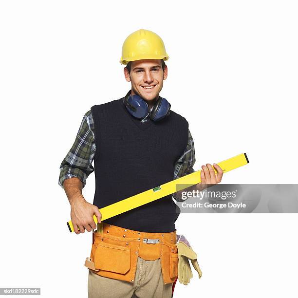 portrait of a man wearing a tool belt and carrying a spirit level - male using spirit level photos et images de collection