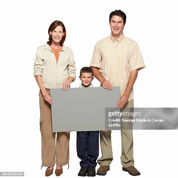 portrait of parents and son (8-9) holding blank placard between them - between stock-fotos und bilder