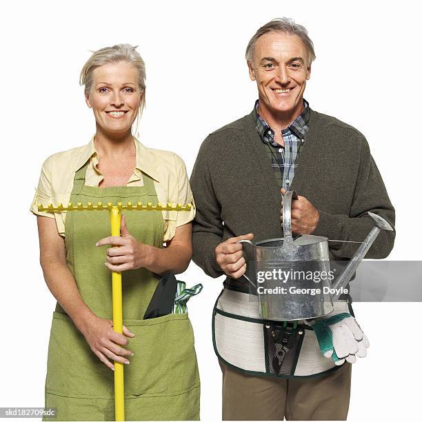 portrait of a woman holding a rake and a man holding a watering can - pitorro fotografías e imágenes de stock
