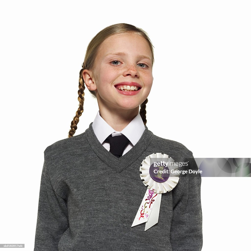 Portrait of a girl (10-12) wearing a school uniform with a rosette on her jumper