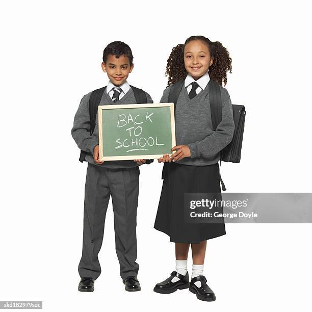 close up of a boy (9-10) and girl (11-12) standing holding a 'back to school' chalkboard between them - between stock-fotos und bilder