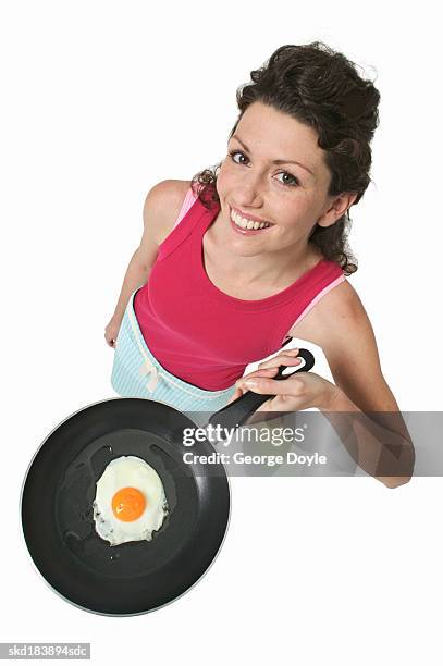 elevated portrait of a woman holding a frying pan with an egg in it - pan stock-fotos und bilder