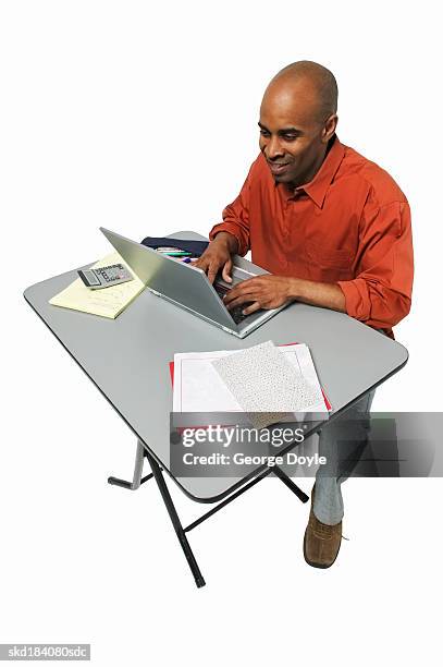 elevated view of a male student typing on a laptop - happy male side view stock-fotos und bilder