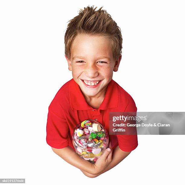 elevated view of a boy (9-10) smiling and holding a jar of candy - candy jar stock pictures, royalty-free photos & images