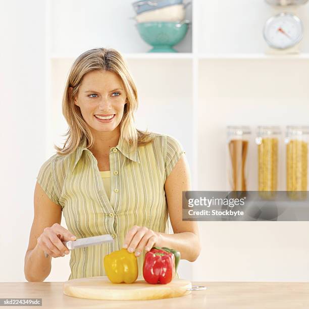 front view of young woman cutting bell peppers - bell fotografías e imágenes de stock