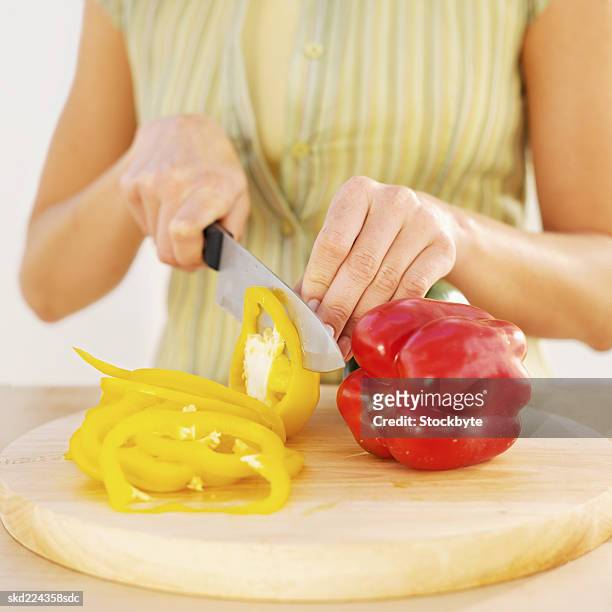 front view mid section of young woman cutting bell peppers - bell foto e immagini stock
