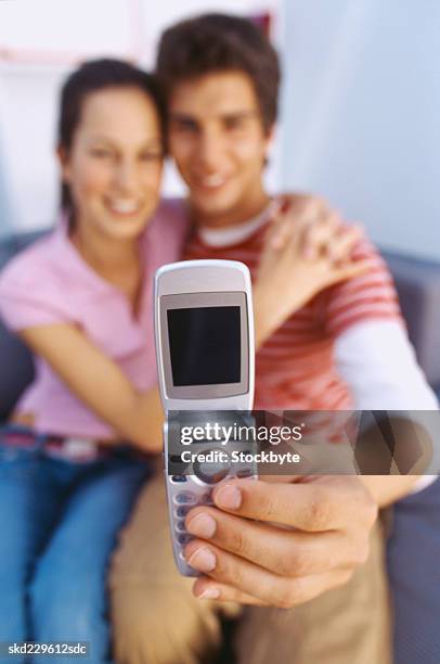 front view of a young couple using a camera phone to take a picture of themselves - camera picture ストックフォトと画像
