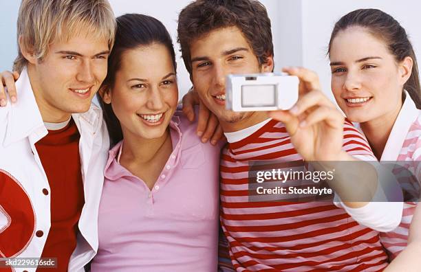 two young couples using a digital camera to take a picture of themselves - camera picture ストックフォトと画像