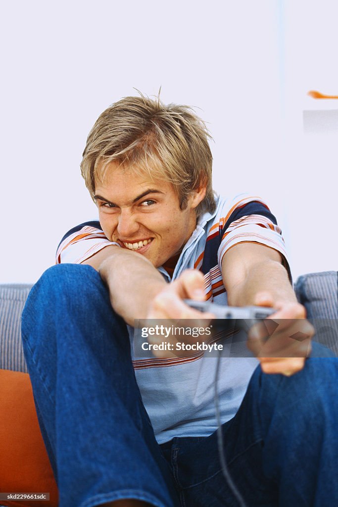 Portrait of a young man sitting on a couch and playing a video game