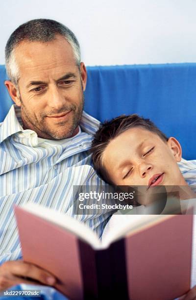 close-up of father reading story to son (10-11) - bedtime stories stock-fotos und bilder