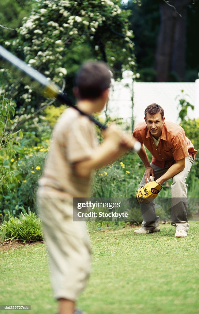 Father and son playing baseball in garden (10-11)