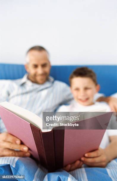 close-up of father reading story to son (10-11) - bedtime stories stock-fotos und bilder