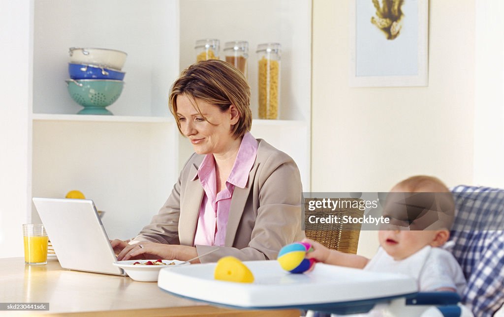 Side view of mother having breakfast with baby girl sitting in high chair (6-12 months)