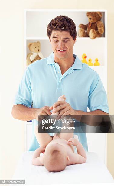 front view of father changing baby boy's nappy (6-12 months) - genderblend stock-fotos und bilder