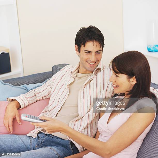 close-up of young couple sitting on sofa and holding remote control - control photos et images de collection