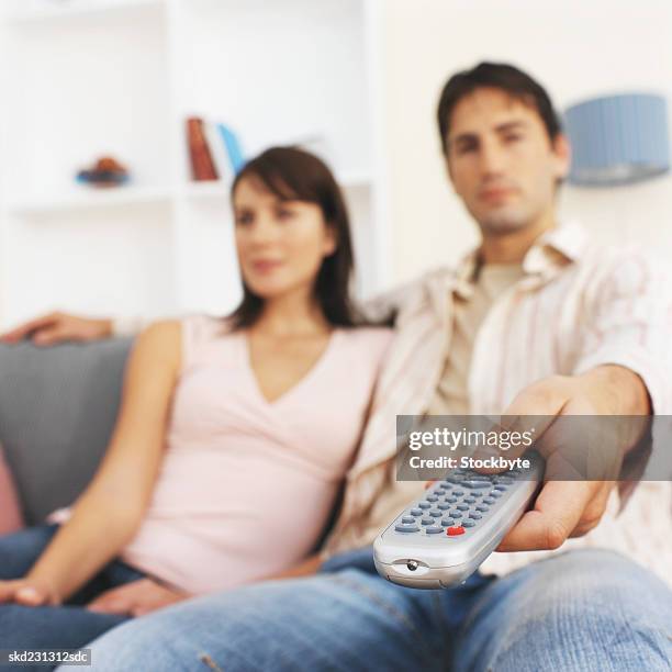 close-up of young couple sitting on sofa and holding remote control - control photos et images de collection