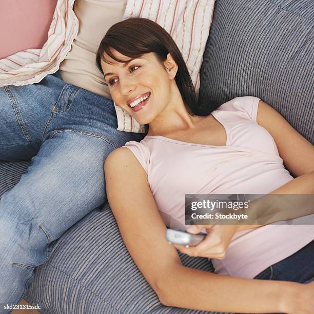 close-up of young couple sitting on sofa and holding remote control - control photos et images de collection
