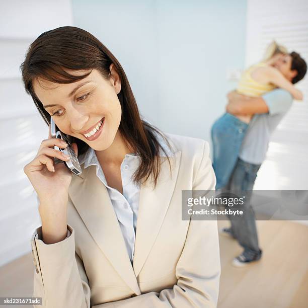 real estate agent talking on a mobile phone after selling a house to a delighted couple - commercial event stockfoto's en -beelden