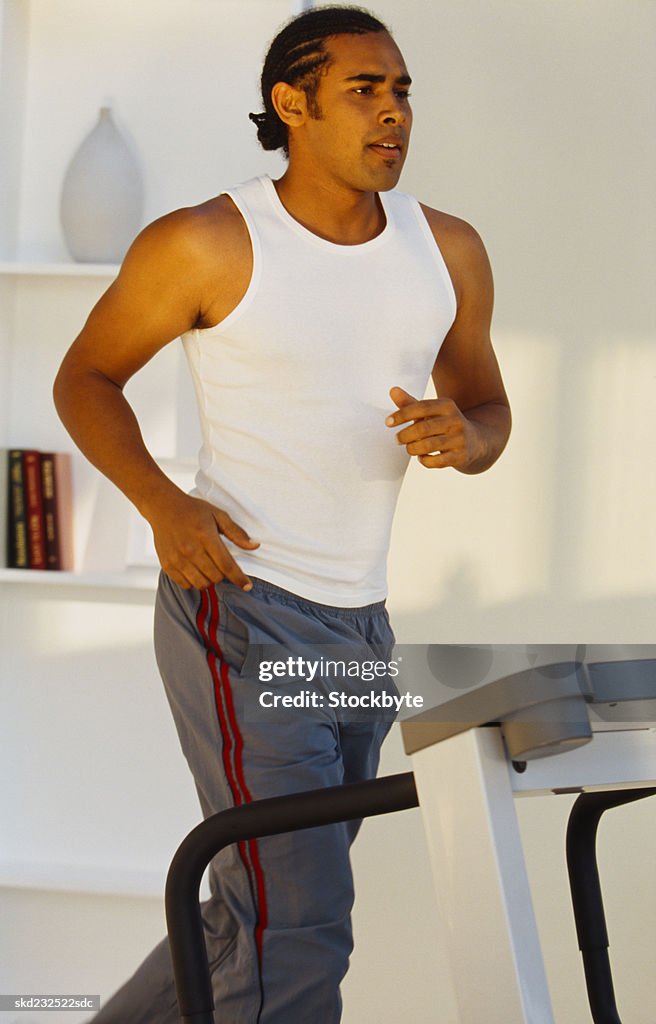 Side profile of a young man jogging on a treadmill