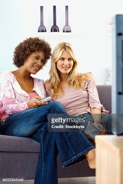 close-up of two young women sitting on sofa and holding remote control - control photos et images de collection