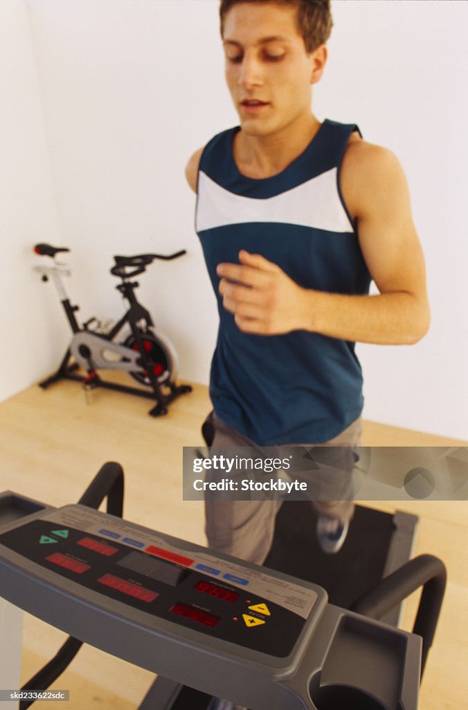 Close-up of a young man jogging on a treadmill