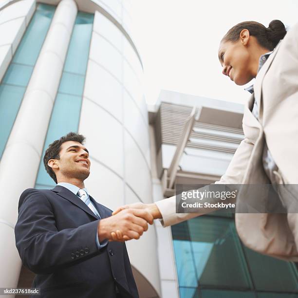 low angle view of two business executives shaking hands - open roads world premiere of mothers day arrivals stockfoto's en -beelden