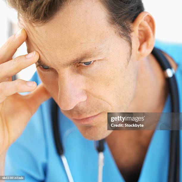 close-up of a mid adult surgeon with his head resting on his hand - hand on head ストックフォトと画像