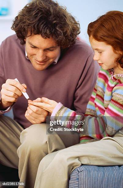 man removing blood from a young girl's (8-10) finger - genderblend stock pictures, royalty-free photos & images