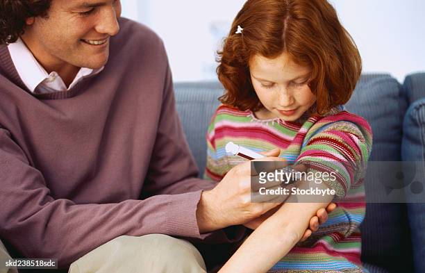 close-up of a man injecting a young girl (8-10) in the arm - genderblend stock-fotos und bilder