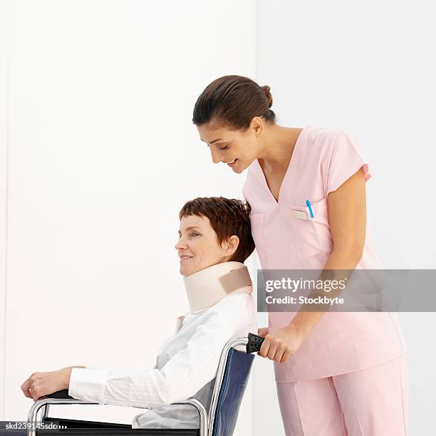 side view of a young nurse pushing mature patient in wheelchair - pushing wheelchair stock pictures, royalty-free photos & images