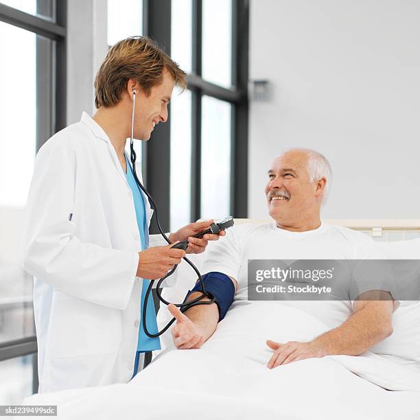 mid adult doctor taking blood pressure of mature patient - rapporto medico paziente foto e immagini stock