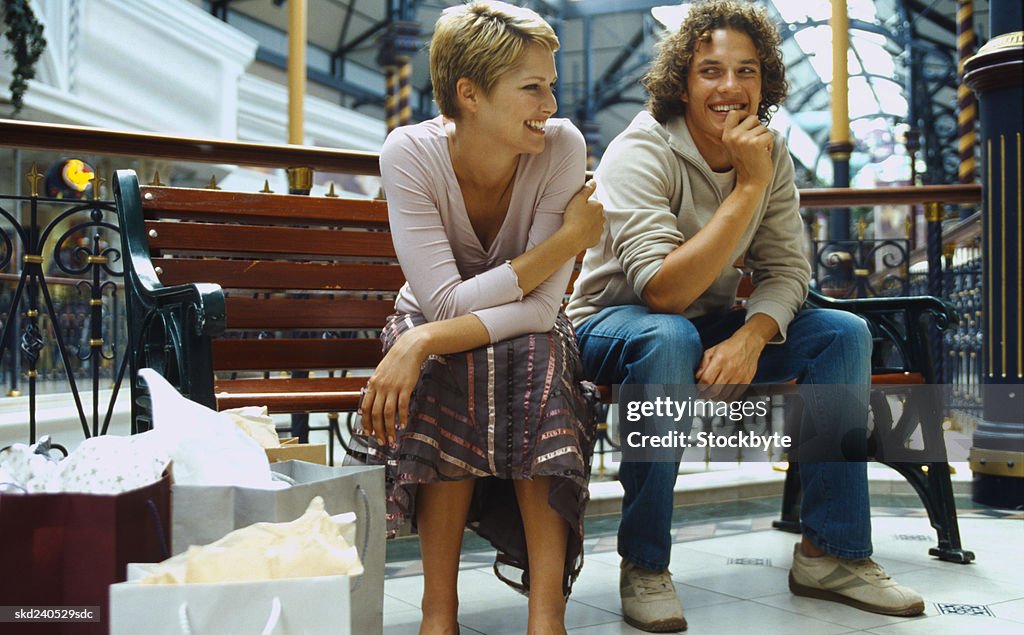 Young couple sitting on a bench in a shopping mall
