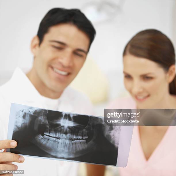 close-up of dentist and dental nurse examining x-ray - dental imaging stock pictures, royalty-free photos & images