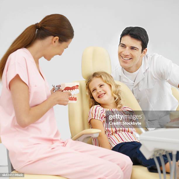 close-up of dentist and dental nurse showing girl how to wash his teeth using model teeth (8-9) - how fotografías e imágenes de stock